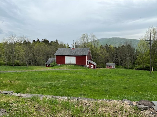 1302 Swart Rd, Middletown, NY 12455 - view of green lawn with an outbuilding, a barn, a view of trees, a detached garage, and a mountain view