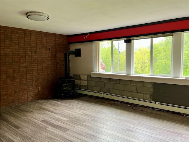 1302 Swart Rd, Middletown, NY 12455 - unfurnished room featuring a wood stove, plenty of natural light, brick wall, and light wood-type flooring