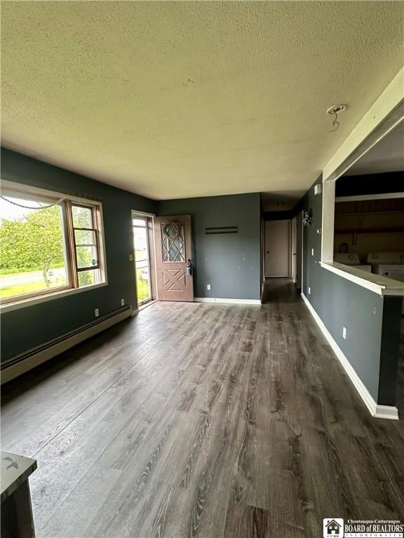 538 Erie St, Olean-City, NY 14760 - unfurnished living room featuring baseboard heating, a textured ceiling, wood finished floors, and baseboards