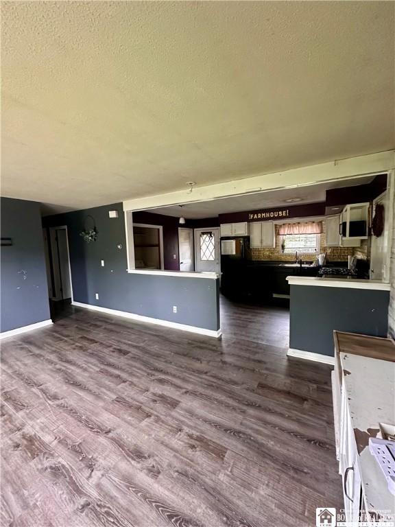 538 Erie St, Olean-City, NY 14760 - unfurnished living room featuring a textured ceiling, dark wood finished floors, baseboards, and a sink