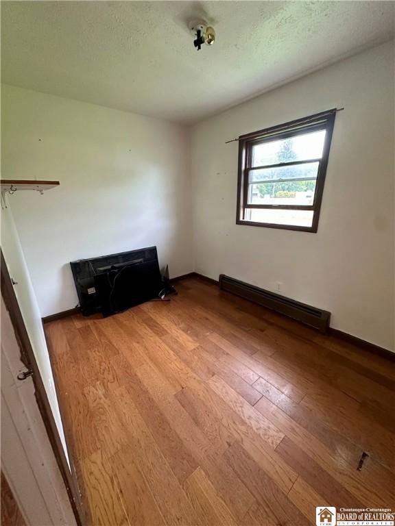 538 Erie St, Olean-City, NY 14760 - spare room featuring baseboard heating, hardwood / wood-style flooring, and baseboards