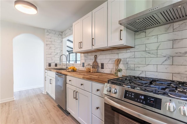 22 Idyllwood Ln, Irondequoit, NY 14617 - kitchen featuring ventilation hood, stainless steel appliances, butcher block countertops, a sink, and arched walkways