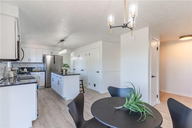 82 Haskins Ln N, Greece, NY 14468 - kitchen with freestanding refrigerator, dark countertops, light wood finished floors, white cabinets, and a center island