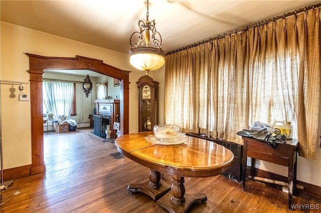 49 Mercer Ave, Buffalo, NY 14214 - dining space featuring a baseboard heating unit, wood finished floors, baseboards, a fireplace, and a baseboard radiator
