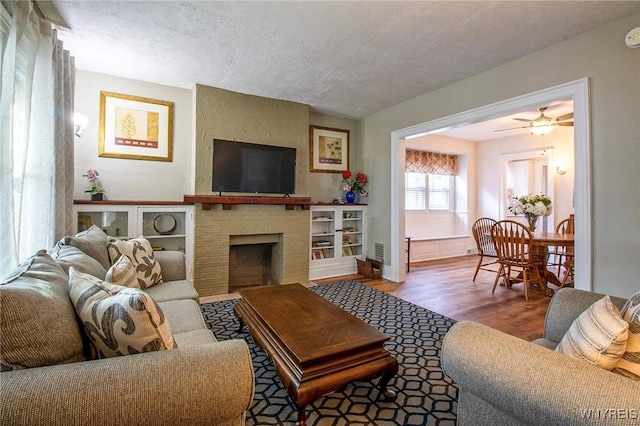 624 Buffalo Ave, Niagara Falls, NY 14303 - living area with wood finished floors, a textured ceiling, a fireplace, a ceiling fan, and baseboards