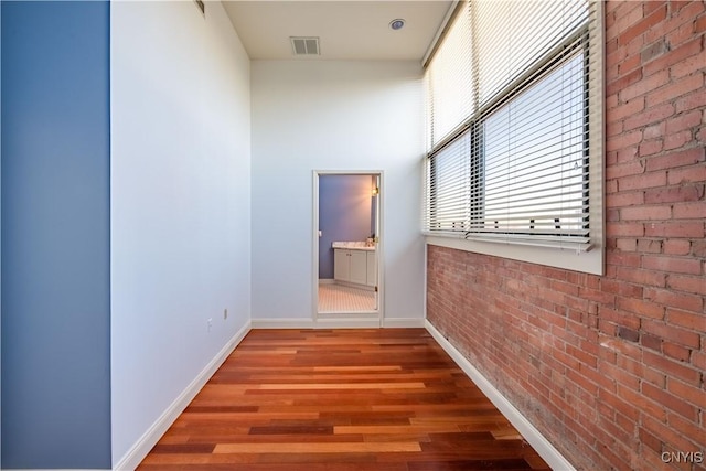 526 Plum St Unit 408, Syracuse, NY 13204 - hallway featuring baseboards, wood finished floors, and brick wall
