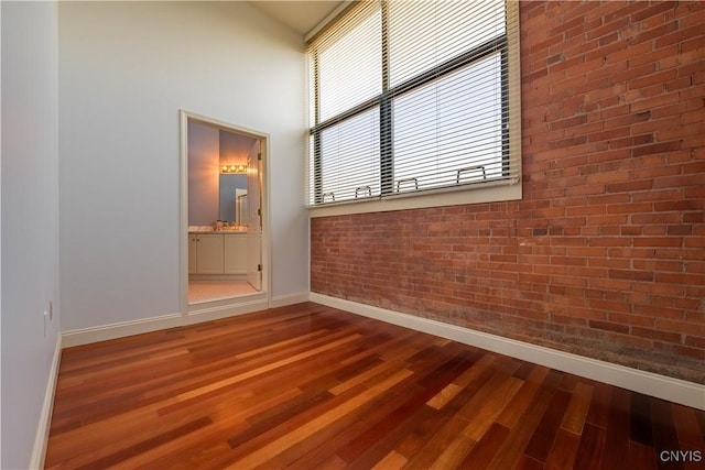 526 Plum St Unit 408, Syracuse, NY 13204 - spare room with baseboards, wood finished floors, brick wall, and a towering ceiling