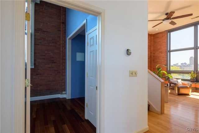 526 Plum St Unit 408, Syracuse, NY 13204 - corridor featuring wood finished floors, an upstairs landing, baseboards, brick wall, and a view of city