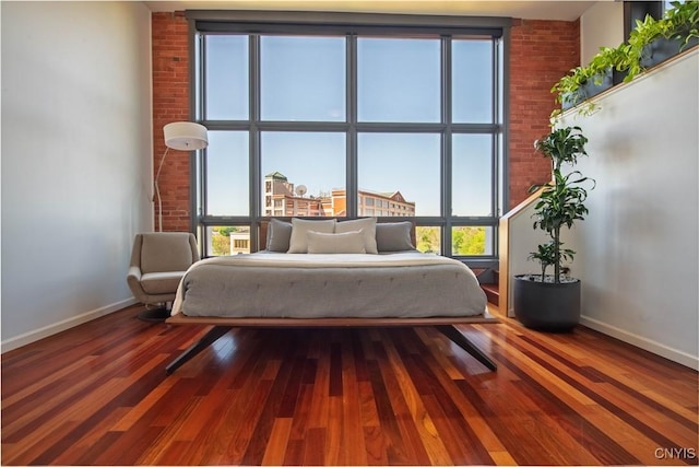 526 Plum St Unit 408, Syracuse, NY 13204 - bedroom featuring baseboards, wood finished floors, and brick wall