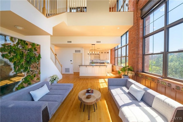 526 Plum St Unit 408, Syracuse, NY 13204 - living area with a high ceiling, light wood-style floors, stairs, and a chandelier
