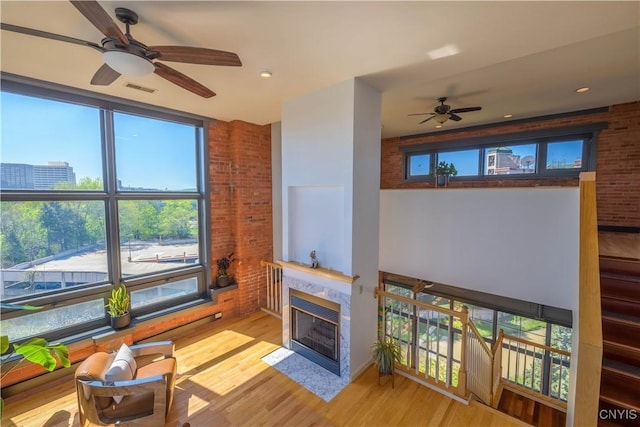 526 Plum St Unit 408, Syracuse, NY 13204 - living area with a ceiling fan, brick wall, light wood finished floors, and a tile fireplace