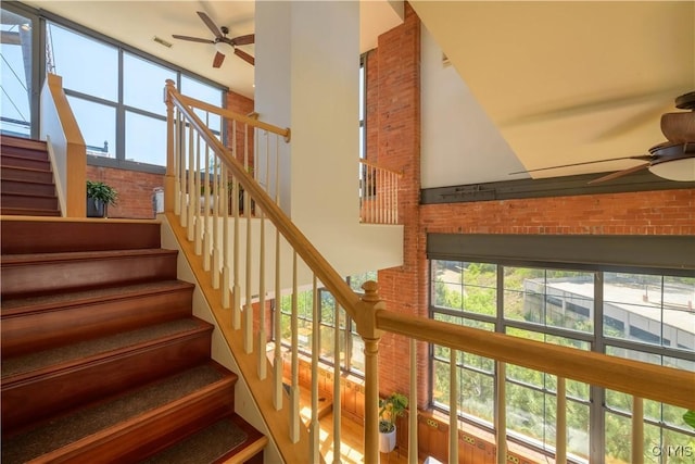 526 Plum St Unit 408, Syracuse, NY 13204 - stairs featuring a ceiling fan, a high ceiling, and brick wall
