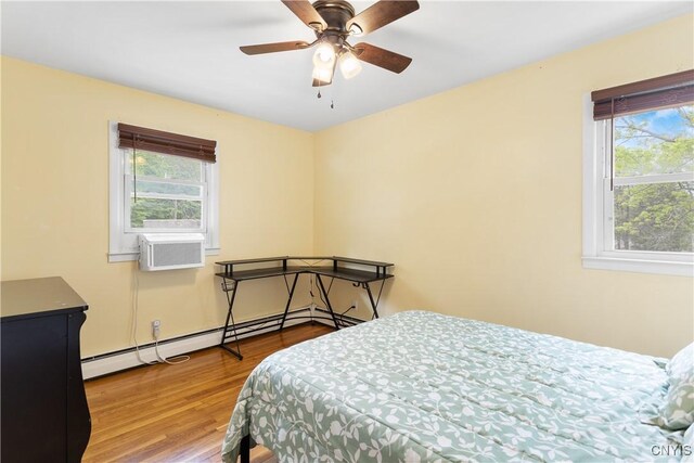 27 Cascade Dr, New Hartford, NY 13413 - bedroom with multiple windows, wood finished floors, cooling unit, and a baseboard heating unit
