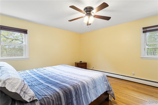 27 Cascade Dr, New Hartford, NY 13413 - bedroom with wood finished floors, baseboard heating, and a ceiling fan