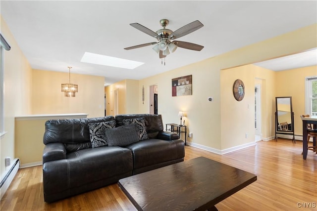 27 Cascade Dr, New Hartford, NY 13413 - living room with baseboard heating, a chandelier, ceiling fan, light wood-style floors, and a skylight