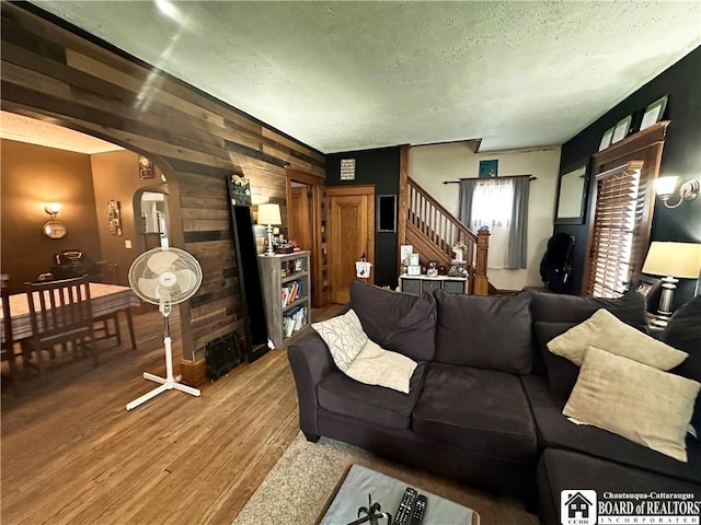 223 S 7th St, Olean-City, NY 14760 - living area featuring wooden walls, arched walkways, wood finished floors, a textured ceiling, and stairs