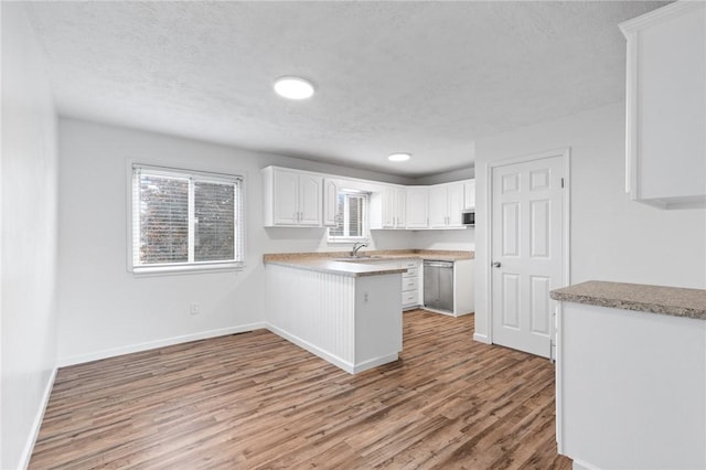 275 Owens Rd Unit 115, Sweden, NY 14420 - kitchen with a peninsula, white cabinets, light wood-type flooring, a textured ceiling, and a sink