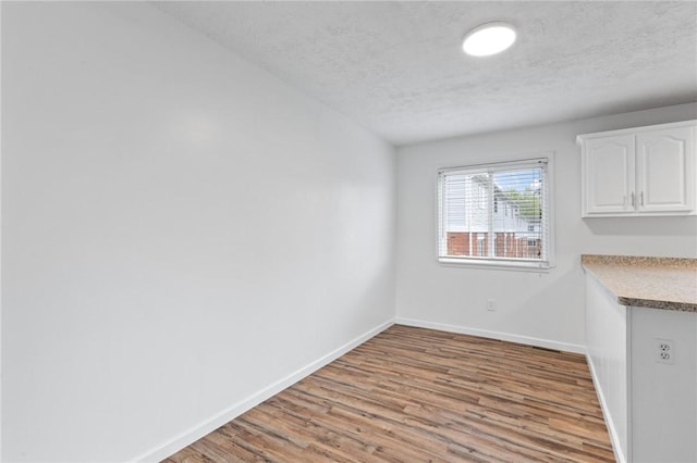 275 Owens Rd Unit 115, Sweden, NY 14420 - unfurnished dining area with wood finished floors, baseboards, and a textured ceiling