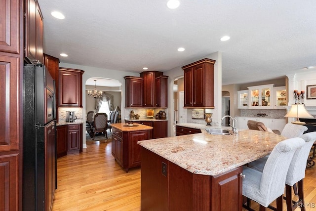 1968 Penfold Way, Lysander, NY 13027 - kitchen with freestanding refrigerator, arched walkways, a sink, light wood-type flooring, and a center island