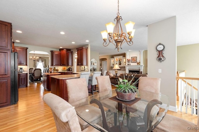 1968 Penfold Way, Lysander, NY 13027 - dining area featuring a chandelier, arched walkways, light wood-style floors, recessed lighting, and a fireplace