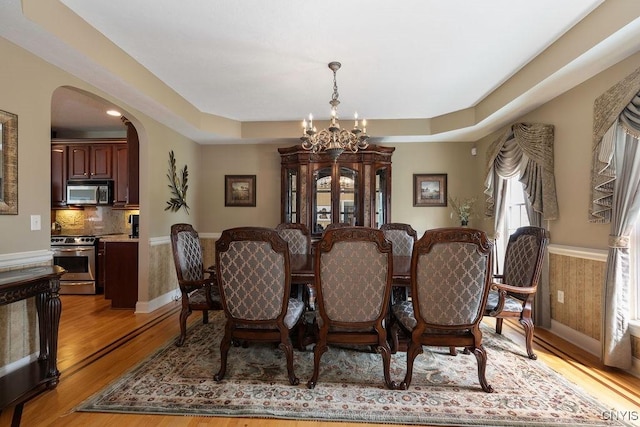 1968 Penfold Way, Lysander, NY 13027 - dining space with a chandelier, arched walkways, light wood-style floors, wainscoting, and baseboards