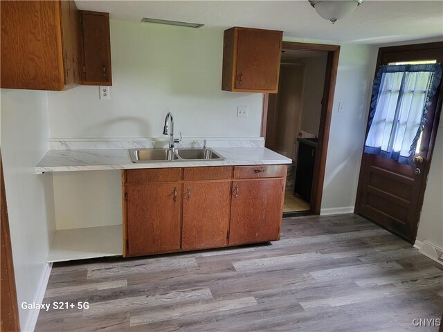 8723 E Mud Lake Rd, Lysander, NY 13027 - kitchen with a sink, light countertops, light wood-type flooring, brown cabinetry, and baseboards