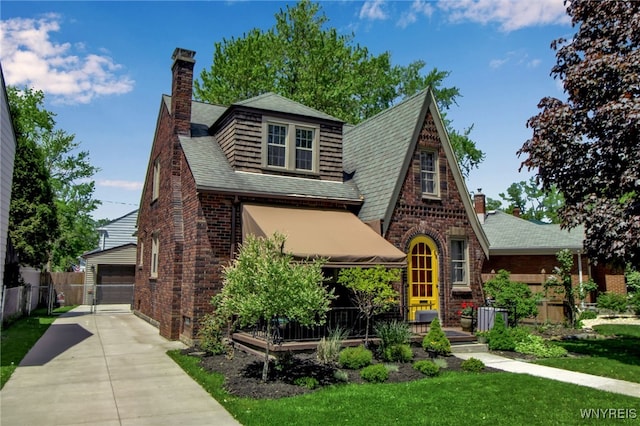 88 Garland Dr, Amherst, NY 14226 - tudor-style house featuring a chimney, brick siding, a shingled roof, and an outdoor structure