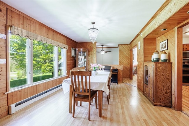 7425 Eelpot Rd, Naples, NY 14512 - dining area featuring baseboard heating, wood walls, a chandelier, light wood-type flooring, and crown molding