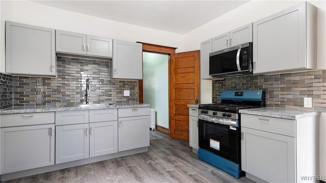 54 Meech Ave, Buffalo, NY 14208 - kitchen with appliances with stainless steel finishes, a sink, light wood-style flooring, tasteful backsplash, and light stone counters