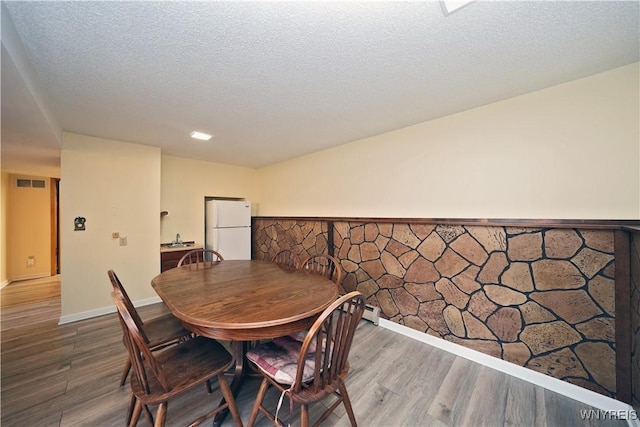 704 Beach Rd, Evans, NY 14006 - dining room featuring wood finished floors, wainscoting, and a textured ceiling