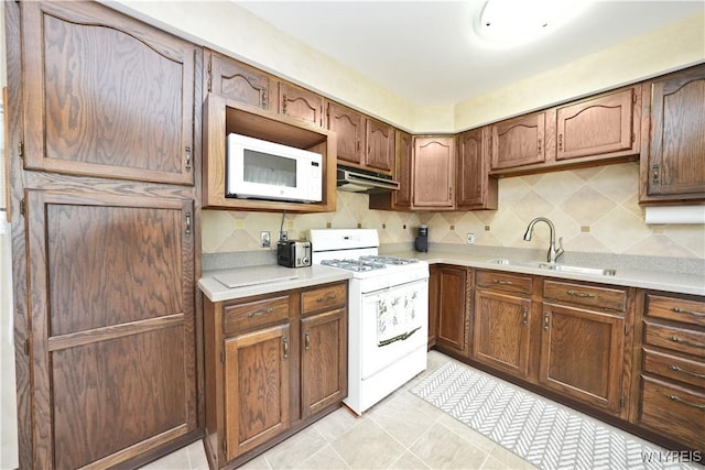 704 Beach Rd, Evans, NY 14006 - kitchen featuring white appliances, under cabinet range hood, a sink, light countertops, and tasteful backsplash