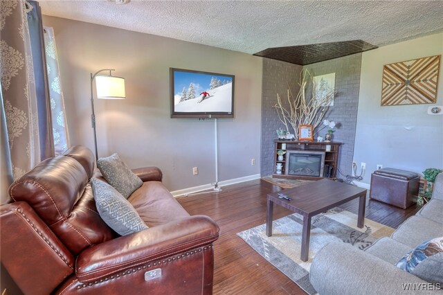 26 Pine Tree Village Rd Unit 26, Ellicottville, NY 14731 - living room with a textured ceiling, baseboards, a glass covered fireplace, and wood finished floors