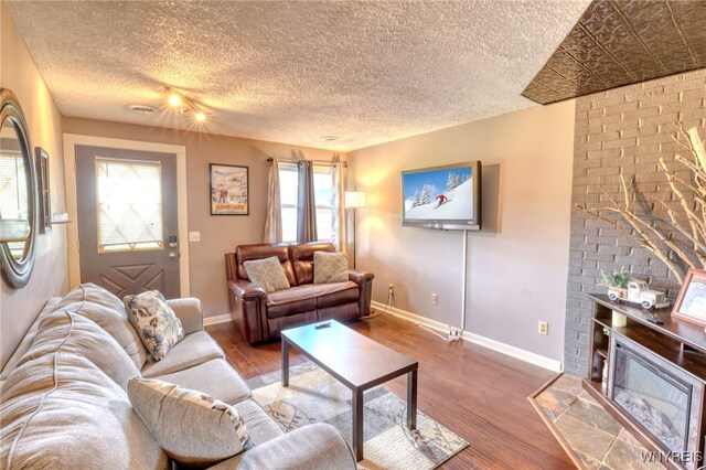 26 Pine Tree Village Rd Unit 26, Ellicottville, NY 14731 - living area with baseboards, wood finished floors, a fireplace, and a textured ceiling