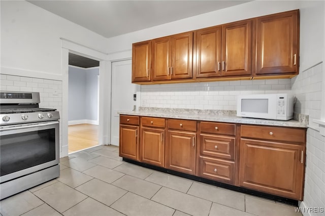 75 N Park Ave, Buffalo, NY 14216 - kitchen with stainless steel gas range, white microwave, brown cabinets, tasteful backsplash, and light tile patterned floors