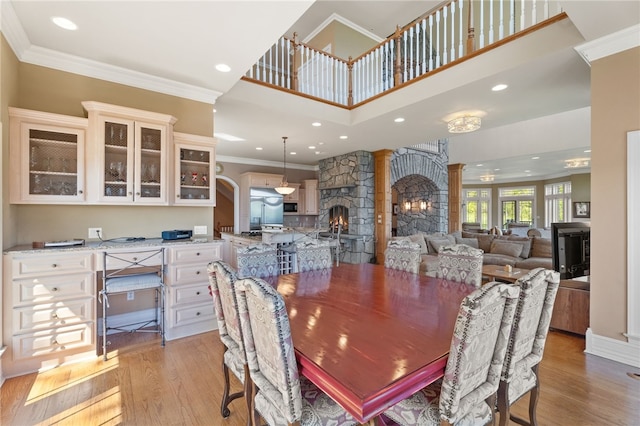 436 Steuben St, Reading, NY 14891 - dining space featuring decorative columns, light wood-style flooring, crown molding, a stone fireplace, and arched walkways