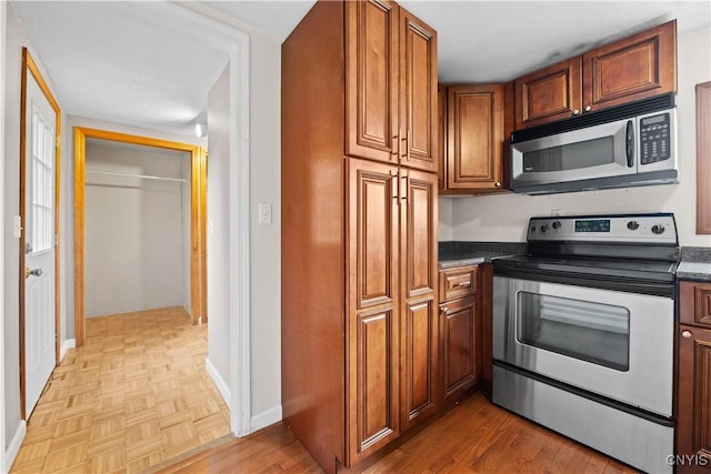 3583 W Seneca Tpke, Onondaga, NY 13215 - kitchen with appliances with stainless steel finishes, brown cabinetry, baseboards, and parquet floors