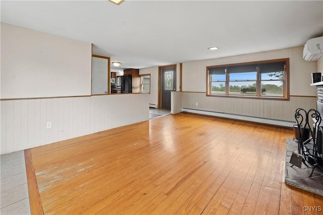 3583 W Seneca Tpke, Onondaga, NY 13215 - unfurnished living room featuring a wall mounted AC, a baseboard heating unit, light wood finished floors, and wainscoting