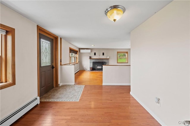 3583 W Seneca Tpke, Onondaga, NY 13215 - foyer entrance featuring baseboard heating, light wood-style flooring, a wall unit AC, a brick fireplace, and baseboards