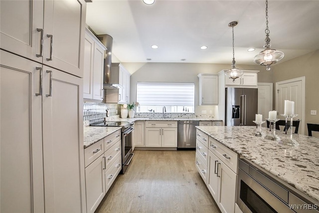 5692 Ferncrest Ct Unit B, Clarence, NY 14032 - kitchen with premium appliances, wall chimney exhaust hood, light wood-type flooring, recessed lighting, and light stone countertops