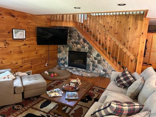 103 Onondaga Rd, Webb, NY 13420 - living room featuring stairway, a fireplace, wooden walls, and wood finished floors
