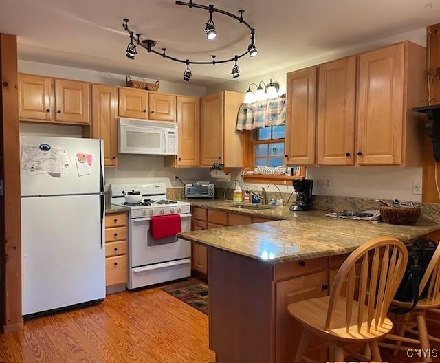 103 Onondaga Rd, Webb, NY 13420 - kitchen with white appliances, a peninsula, light brown cabinetry, a kitchen breakfast bar, and a sink