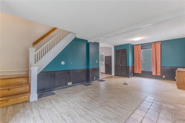 10 Garfield St Unit 10, Cortland, NY 13045 - unfurnished living room with stairs, a wainscoted wall, and wood finished floors