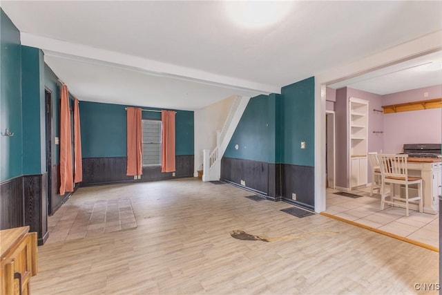 10 Garfield St Unit 10, Cortland, NY 13045 - unfurnished living room with wainscoting, wood finished floors, beam ceiling, and stairs