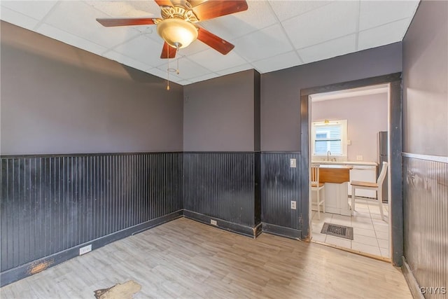 10 Garfield St Unit 10, Cortland, NY 13045 - unfurnished room with wood finished floors, a paneled ceiling, a ceiling fan, wainscoting, and a sink