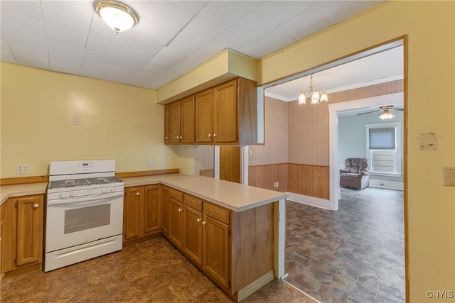 10 Garfield St Unit 10, Cortland, NY 13045 - kitchen featuring white range with gas cooktop, a peninsula, light countertops, a chandelier, and wooden walls