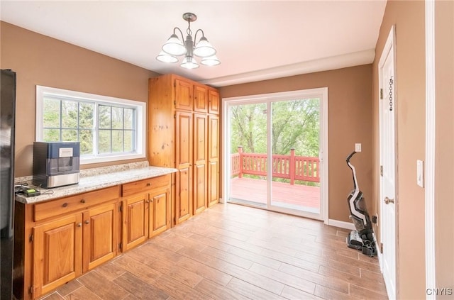 8929 State Route 12e, Lyme, NY 13622 - kitchen with a chandelier, light wood-style flooring, light stone counters, hanging light fixtures, and freestanding refrigerator