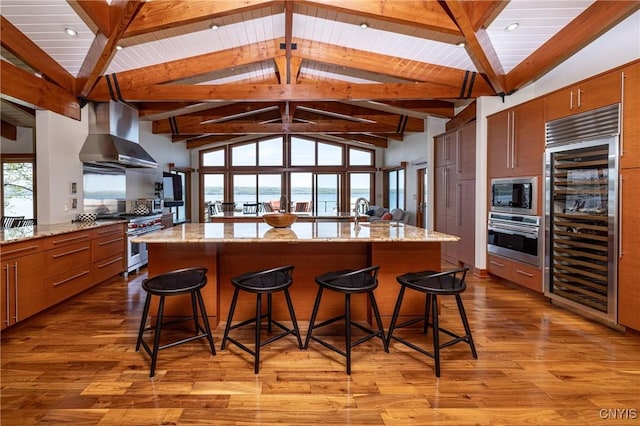 9182 S Rhodes Rd, Lodi, NY 14860 - kitchen featuring appliances with stainless steel finishes, wall chimney exhaust hood, beverage cooler, light wood-type flooring, and a breakfast bar