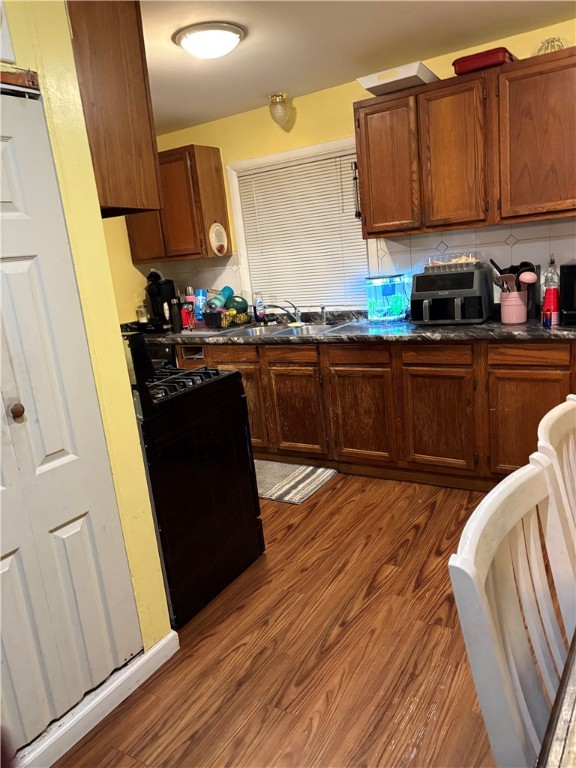 399 Electric Ave, Rochester, NY 14613 - kitchen with black gas range, dark countertops, dark wood finished floors, a sink, and tasteful backsplash
