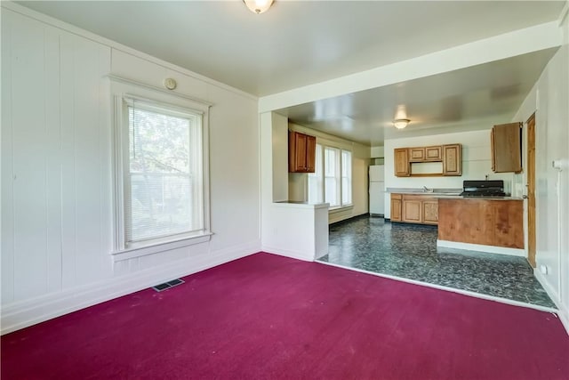 475 Sherman St, Rochester, NY 14606 - kitchen with stove, brown cabinets, freestanding refrigerator, a sink, and baseboards