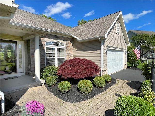 4166 Angela Way, Gorham, NY 14424 - view of property exterior featuring roof with shingles, a garage, stone siding, and asphalt driveway